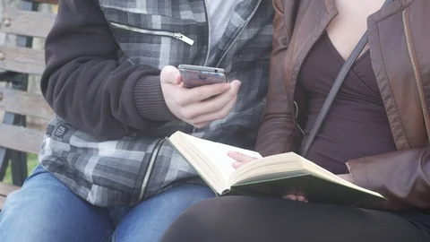 Using a smartphone and reading a book Stock Footage 88863480