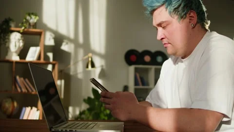 Using smartphone and typing on laptop keyboard close-up. Man with blue hair Video stock 180549058