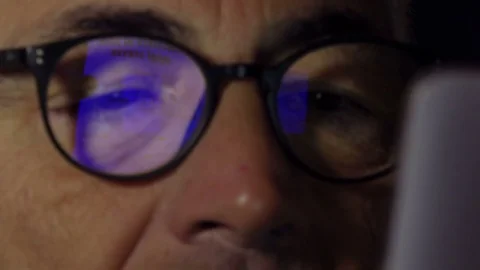 Using smartphone with blue reflections on glasses of a mid aged man Video stock 74429929