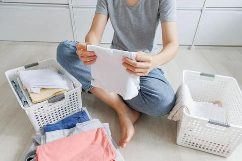 Using a smartphone during a home laundry routine. People check a mobile pho.. Stock Photos
