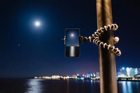 Using smartphone on flexible tripod to making the photo of sea night landscape Stock Photos