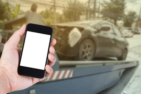 Using smartphone on hand with blurry background of black car on accident on t Stock Photos