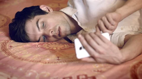 Using smartphone on his bed and sending a sms Video stock 47827813