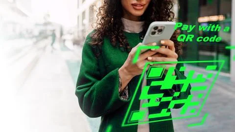 Using a smartphone to make an online payment with a QR code in a busy city Fotos de archivo