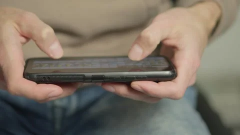 Using a smartphone, a man looks through photos and news, opening a window to the Stock Footage 247503035