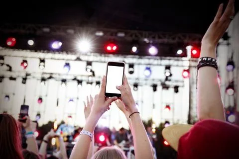Using smartphone at music show. Empty blank white screen for your image. Stock Photos
