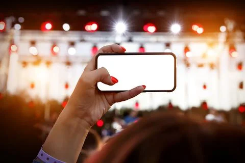 Using smartphone at music show. Empty blank white screen for your image. Stock Photos