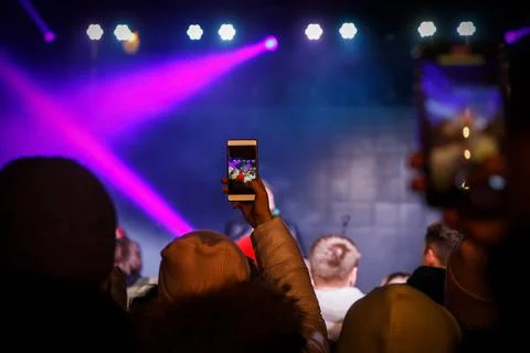 Using a smartphone in a public event. Holding a mobile phone in hands and sho Stock Photos