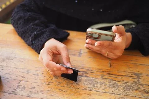 Using a smartphone to scan the QR code in at a wooden table at the cafe Foto stock