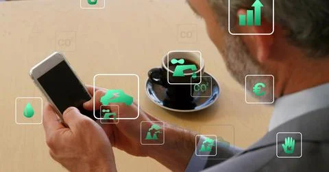 Using smartphone, senior professional in suit viewing green AR icons at cafe Stock Photos