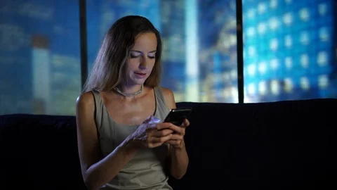 Using Smartphone sitting on the sofa at modern home, relaxing, chatting with Stock Footage 95096486