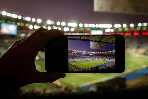 Using a smartphone on soccer stadium. Stock Photos