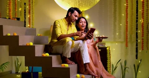 Using smartphone on stairs, Indian couple shops online on Diwali evening Stock Footage 342382000