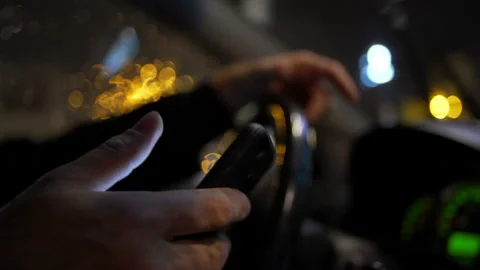 Using smartphone while driving at night in the city Stock Footage 101661000