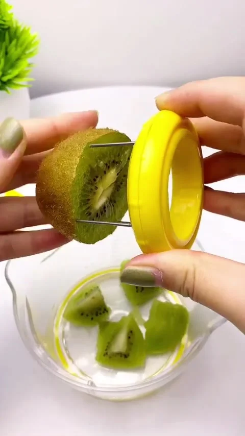 Using a specialized yellow 4-in-1 kiwi slicer tool to peel and slice fruit Stock Footage 340095519