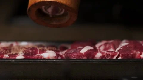 Using spice grinder to sprinkle some pepper on a raw pork meat steak Stock Footage 238904451