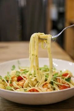 Using stainless fork pick pasta / linguine with scrimp scampi in a white dish Stock Photos