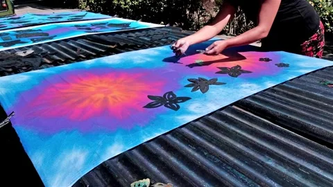 Using stencils onto a tie dye fabric to bleach patterns into the colour Stock Footage 249325556