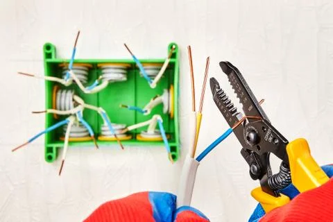 Using a stripper cutter tool for electrical work. Fotos de archivo
