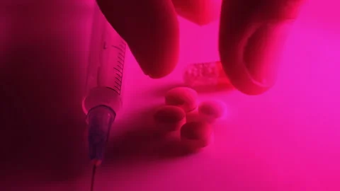 Using a syringe and pills in the red neon light of a nightclub Stock Footage 170599450