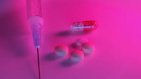 Using a syringe and pills in the red neon light of a nightclub Stock Footage 170599676