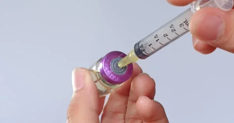 Using syringe suck out of  purple bottle and slowly pulling the medicine. Stock Footage 263574768