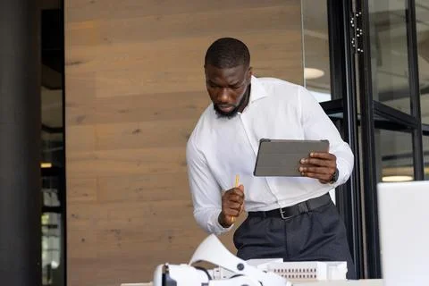 Using tablet and pencil, businessman analyzing architectural model in office 스톡 사진