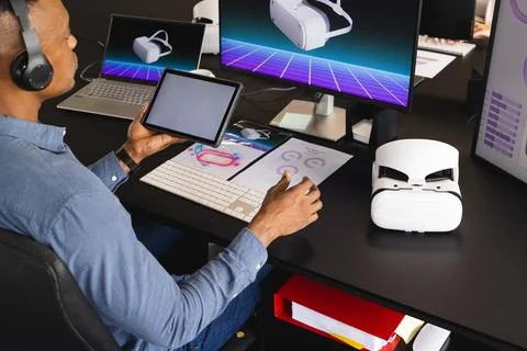 Using tablet and VR headset, man working on virtual reality project in office Stock Photos