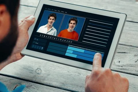Using a tablet to create a deep fake with two faces side by side in a digital Stock Photos