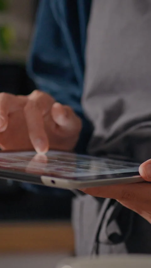 Using a tablet to manage orders in a busy kitchen during lunchtime rush Stock Footage 331732306