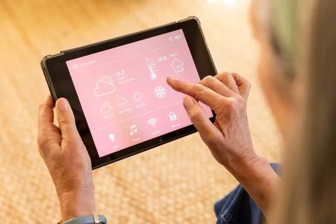 Using tablet, woman controlling smart home settings and monitoring temperature Stock Photos