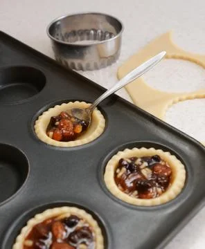Using teaspoon to fill pastry cases with mincemeat Stock Photos