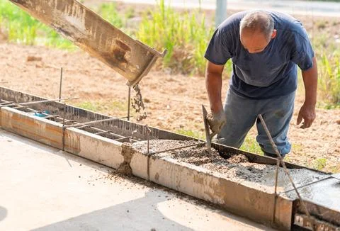 Using trowel worker plasters wet concrete cement wheel stop after Stock-Fotos
