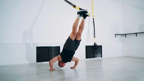 Using TRX bands, doing push-ups with legs suspended. Man is engaged with TRX Stock Footage 114269397