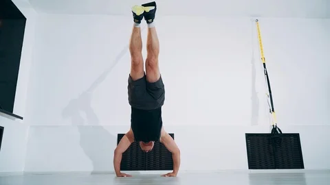 Using TRX bands, doing push-ups with legs suspended. Man is engaged with TRX Stock Footage 114269516