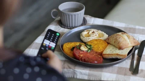 Using TV remote control at meal time, lunch, eating, 4k,real time, cinematic Stockbeeldmateriaal 248542297