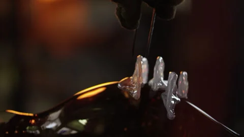 Using tweezers the glass maker creates shapes in the glowing glass Stock Footage 275462634