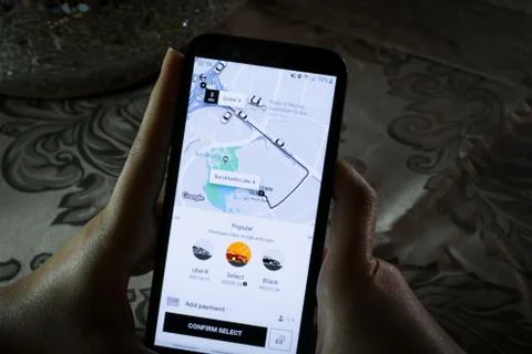 Using the Uber app on a smartphone - City maps and transportation Stock Photos