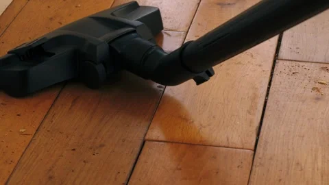 Using vacuum cleaner to clean up dust in home wooden floor Video stock 334107921