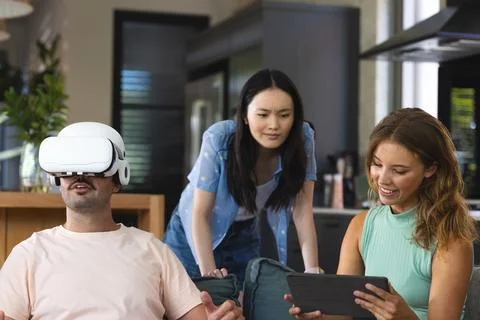 Using virtual reality headset, diverse friends sitting on sofa in living room, Fotos Stock