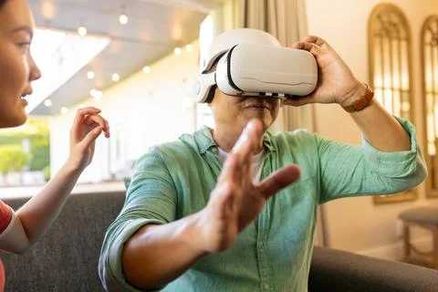 Using VR headset, father exploring virtual reality while daughter guiding him Stock Photos
