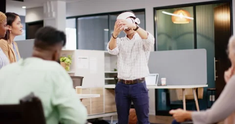Using VR headset, man demonstrating virtual reality to colleagues in office Stock Footage 298824977
