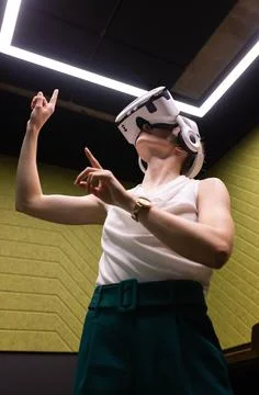 Using VR headset, woman interacting with virtual environment in modern office 스톡 사진