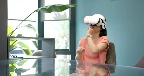 Using VR headset, woman sitting at desk in modern office environment Stock Footage 299884249