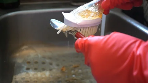 Using a washing brush to wash a fork in spoon with soap Stock Footage 106424119