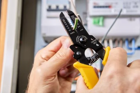 Using wire cutter stripping tool for removal insulation of copper wire from.. Fotos de archivo