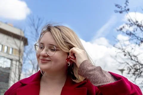 Using wireless headphones. Young plus size woman in red coat wearing headphon Stock Photos