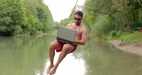 Using work laptop on the beach, swinging over the water Stock Footage 318289463