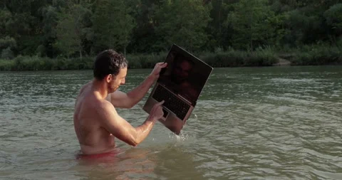 Using work laptop on the beach in the water, rage quit Stock Footage 312465779
