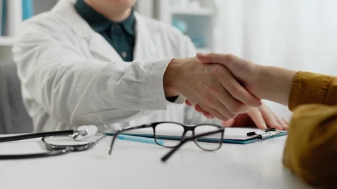 Using. A young European man in a white coat doctor greets the patient with h Stock Footage 252385542